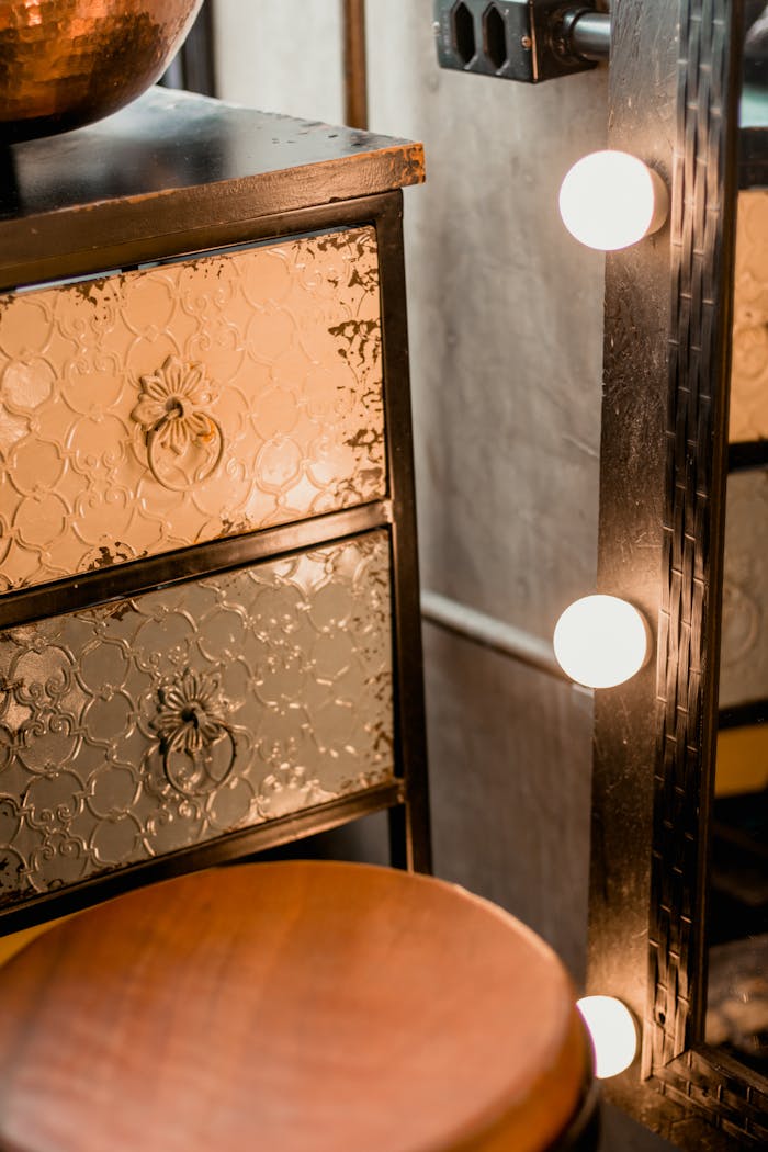 Close-up of a vintage wooden drawer and illuminated mirror in an elegant setting.